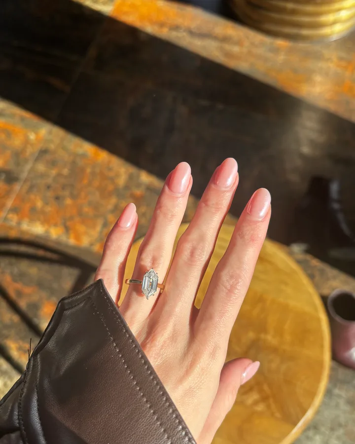 A diamond engagement ring on her finger against a leather sleeve