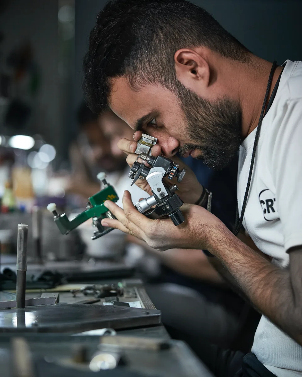 A diamond specialist inspecting a stone through a gem microscope at a cutting bench